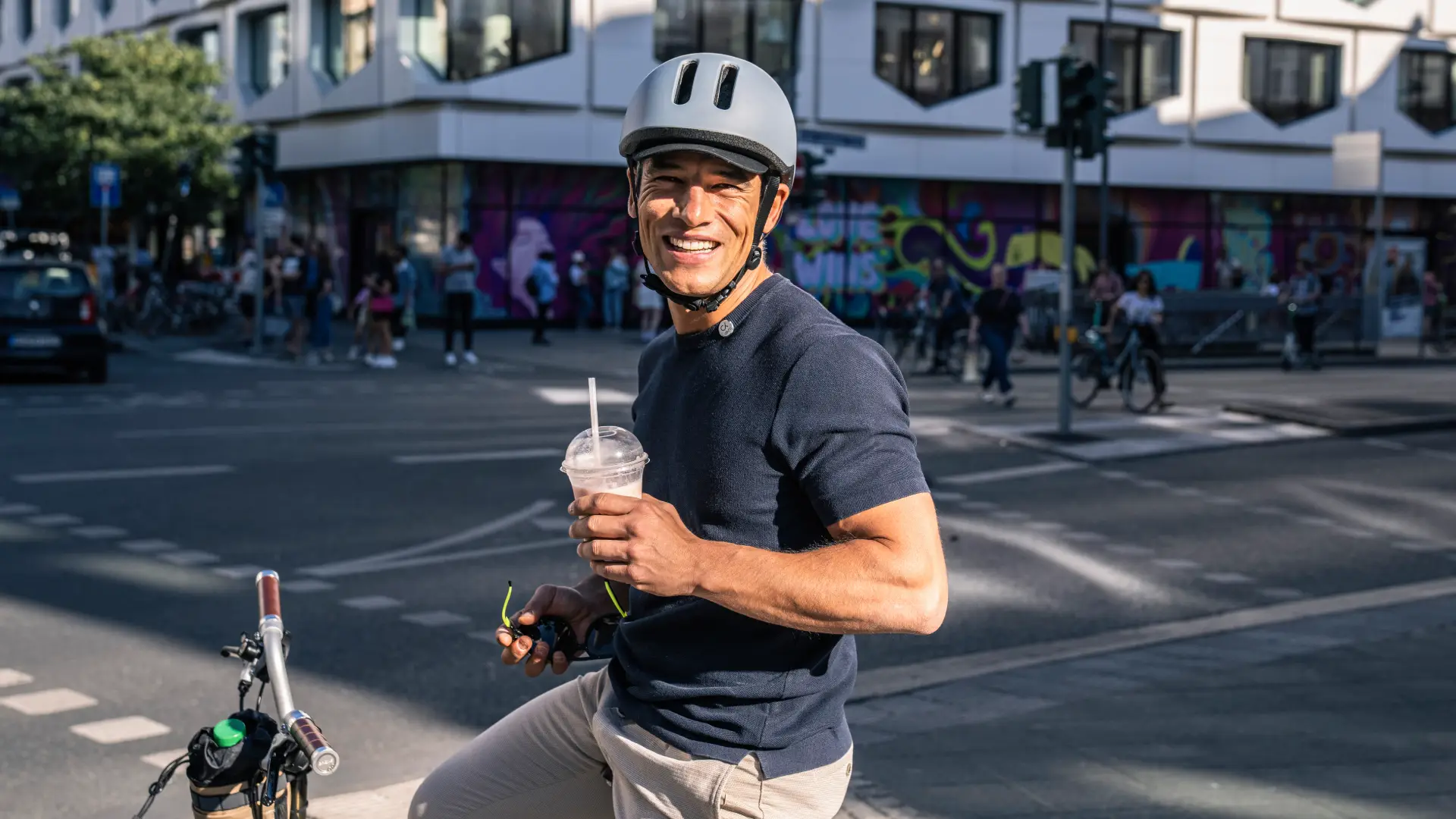 Akro happy cyclist with a Akro helmet drinking a smoothie on a bike with an Akro bag in an urban environment