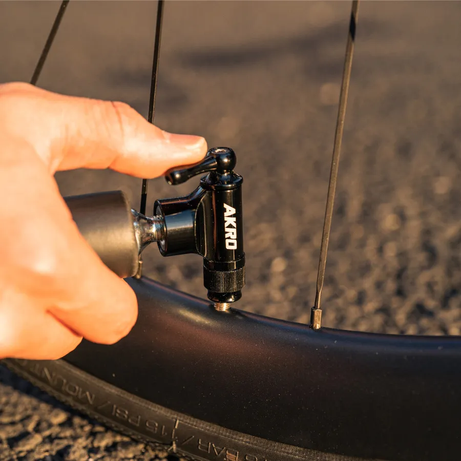 Hand using CO2 Akro Lever inflator to inflate the bicycle tires